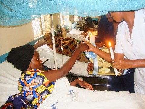 Nurses lighting a candle with a female patient 