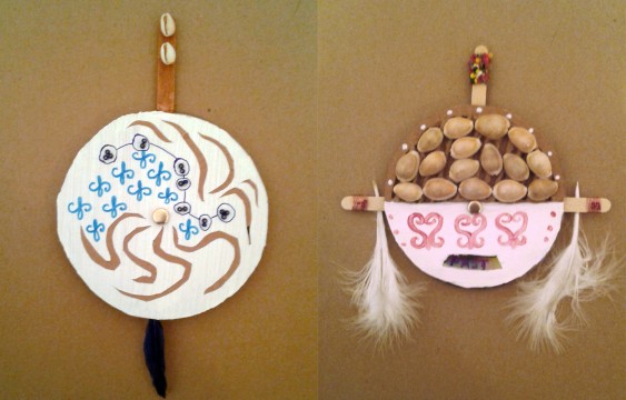 Two unique talismans made from circular cardboard and adorned with shells, decorative marking, beads and feathers