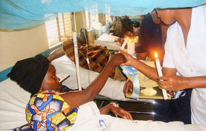 Nurses lighting a candle with a female patient 